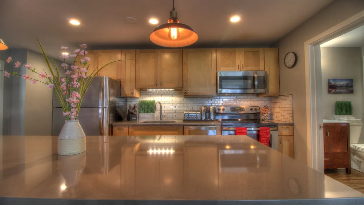 A bright, open kitchen scene featuring a spacious island with a flower vase, sleek stainless steel appliances, and a stylish backsplash. The layout invites easy movement and socializing, and the island is ideal for both cooking and casual dining.